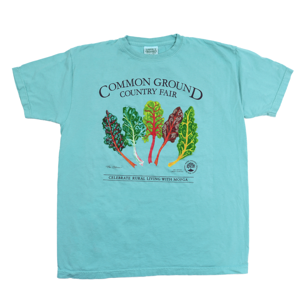 A light blue shirt with artwork in the center depicting a colorful splay of five green, yellow, red, and purple chard. Black text around art reads “Common Ground Country Fair” and  “Celebrate Rural Living with MOFGA”. A black MOFGA logo is in the bottom right corner. 