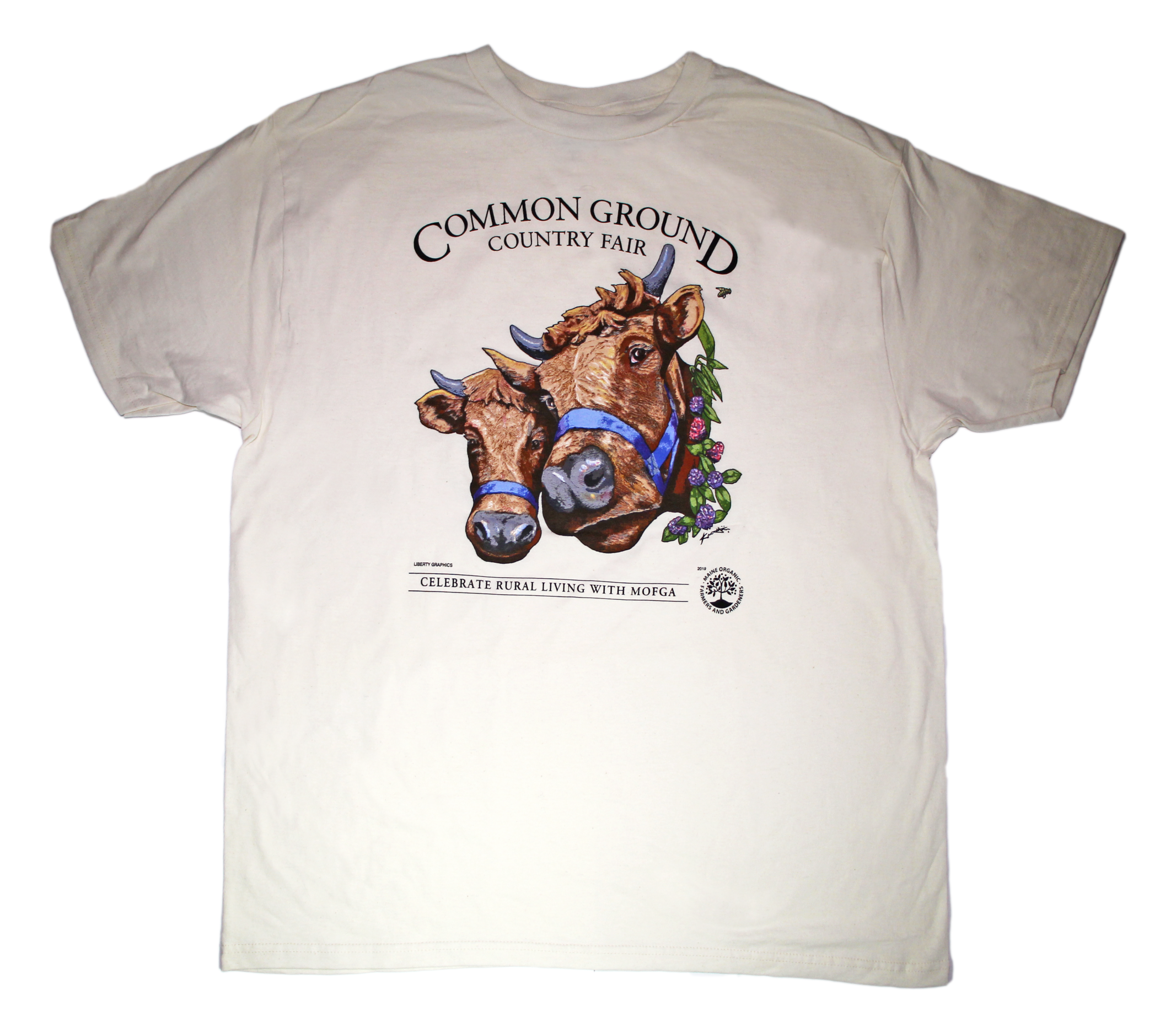 A white shirt with artwork in the center depicting the heads of two shaggy brown cows with horns, wearing blue halters. On the right side of one cow is a viney wreath with small clusters of purple and blush flowers. Black text around art reads “Common Ground Country Fair '' and  “Celebrate Rural Living with MOFGA”. A black MOFGA logo is in the bottom right corner. 